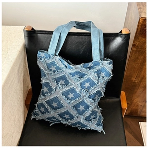 Close-up of denim tote bag featuring star pattern, quilted stitching and frayed fringe details