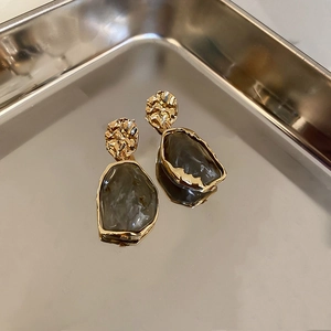 Detail of vintage resin earrings with gold hammered metal and translucent sage pendants