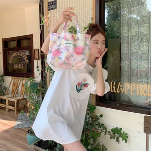 Détail du sac cabas floral et du t-shirt blanc avec broderie de tulipe