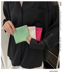 Close-up of small leather coin purses in mint, beige and pink held by a hand