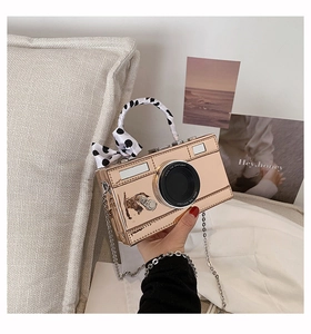 Detail of rose gold camera-shaped mini bag with polka dot ribbon and silver chain strap