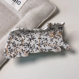Macro view of leopard print acetate hair claw clip on soft beige canvas fabric background