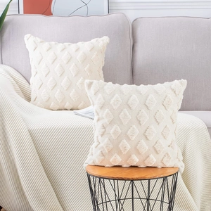 Detail of two cream white plush pillow covers with 3D rhombus texture on a side table
