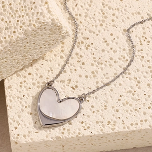 Close-up of heart-shaped shell pendant with 18K gold plating on textured stone