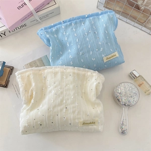 Détail des pochettes cosmétiques en dentelle à paillettes bleu et beige sur coiffeuse