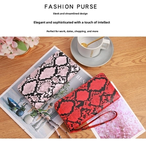 Detail of snake print wallets with detachable wristlets in pink and red color contrast