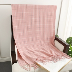 Detailed view of pink plaid scarf with tassels draped over a wooden chair indoors