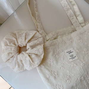 Detail of cream cotton tote bag and scrunchie with delicate floral embroidery
