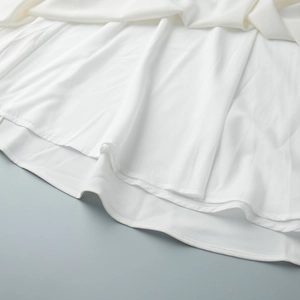 Détail macro de l'ourlet de la robe en mousseline blanche avec couture à double couche