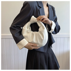 Detail of a creamy white crescent bag with pleated PU leather and knotted handle