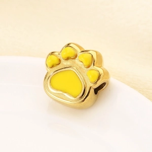 Macro view of a gold stainless steel paw print pendant with yellow enamel detailing