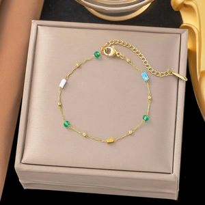 Detalle de pulsera de cadena dorada con piedras naturales de colores y cuenta azul con estrella