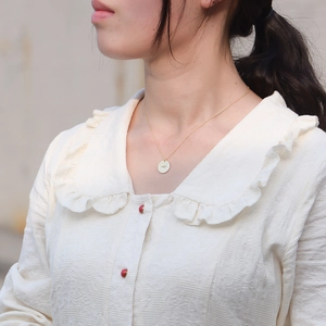 Close-up of gold S925 sterling silver coin necklace featuring a minimalist starburst pendant