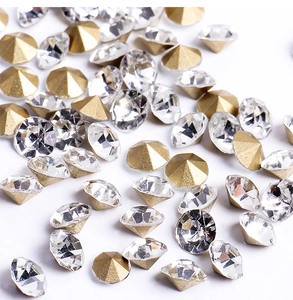 Detailed view of bulk sparkling round cut crystals and golden cone base nail art rhinestones