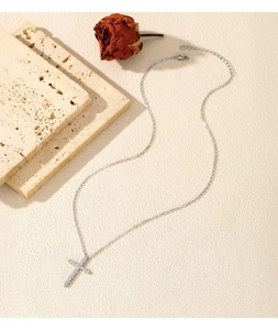 Detailed view of silver cross pendant with VVS1 moissanite stones on a beige stone background