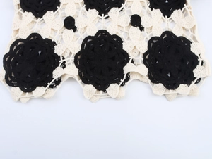 Detailaufnahme von handgefertigtem Häkelstrick mit schwarz-weißem Blumenmuster und Textur