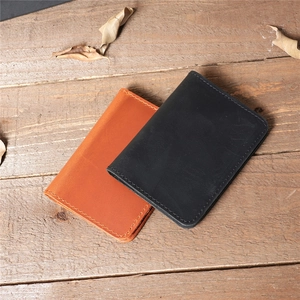 Brown and black crazy horse leather card holders displayed on rustic wooden floor