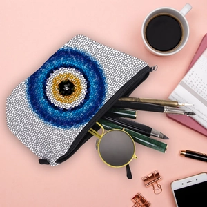 Water-resistant evil eye makeup bag with blue mosaic print on a desktop setting