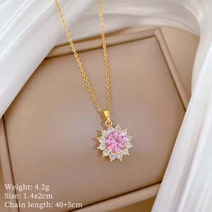Detail of a gold sunflower pendant with a pink center gemstone and tiny clear zircons