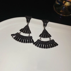 Macro view of black tiered tassel earrings with crystal rhinestones on white tray