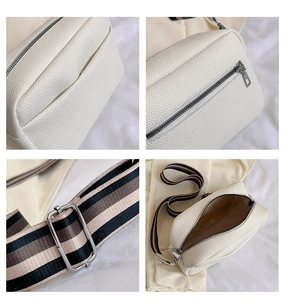Detail view of white pebbled leather crossbody bag with striped wide shoulder strap