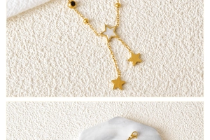 Detail of gold Y-shaped star anklet with shell inlay, tassels, and lobster clasp closure