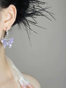 Macro side view of elegant purple butterfly hoop earrings worn on a model's ear