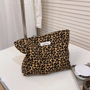 Detailed view of leopard print canvas makeup bag with woven label on a metal tray