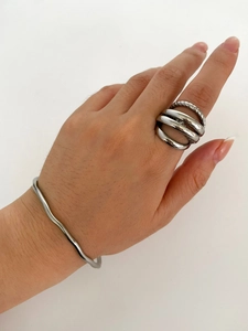Detail of silver multi-layer textured rings and wavy bracelet on model with clean background