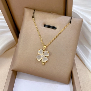 Close-up of golden clover necklace with milky cat-eye stone and crystal on velvet pad