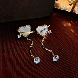 Detailed close-up of heart-shaped shell earrings with gold tassel and zircon accents