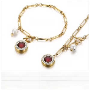 Detailed view of gold stainless steel jewelry set with red stones and pearls on white