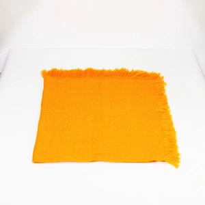 Dettaglio di una sciarpa quadrata in maglia gialla con frange e trama intrecciata