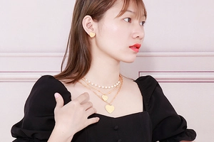 Close-up of a layered gold necklace set with heart pendants and elegant pearl chain detail