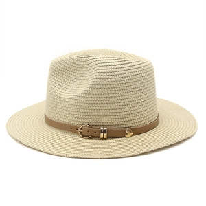 Détail d'un chapeau de paille beige avec bande en cuir et pendentif coeur doré