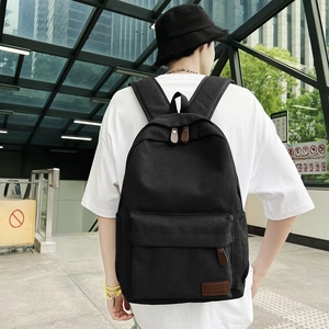 Minimalist black canvas backpack for men and women featuring a leather logo patch
