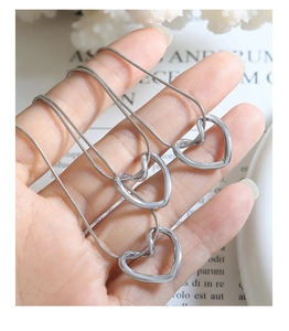 Dettaglio della collana a catena serpente d'argento con tre ciondoli a cuore in metallo