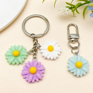 Detail of colorful resin daisy flower charms for DIY jewelry and keychains on beige surface