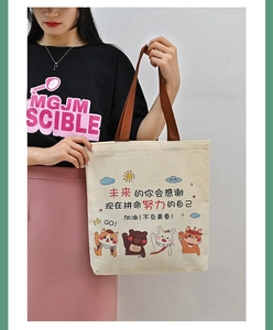 Detail view of cream canvas tote bag with brown handles and colorful cartoon graphics