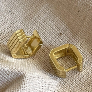 Close-up of geometric square hoop earrings with triple groove texture on linen background