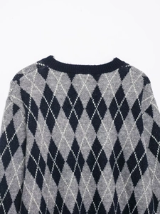 Close-up of argyle knit sweater neckline showing grey, blue, and black diamond patterns