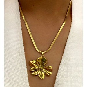 Polished gold flower pendant on snake chain necklace worn by model on white knit top