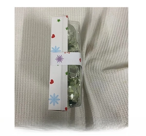 Detailed side view of 28PCS metallic green faceted Christmas ornaments in a clear gift box