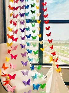 Vibrant butterfly paper garland hanging over a sofa for colorful party decoration