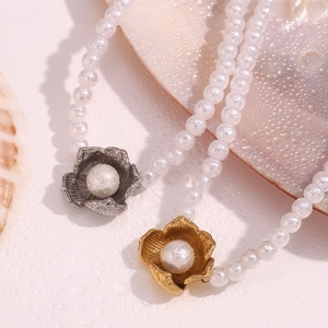 Close-up of pearl necklaces with gold and silver flower pendants on shell surface
