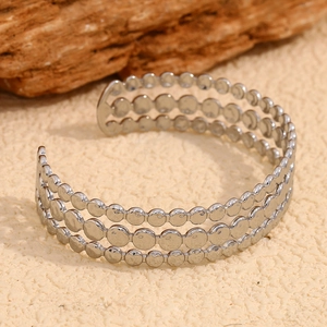 Macro shot of silver three-layer disc bracelet with minimalist open cuff design