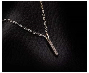 Detailed view of rose gold bar pendant necklace with sparkling diamonds on black leather