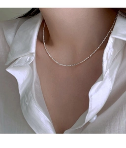 Close-up of minimalist silver plated irregular bead necklace on a white shirt