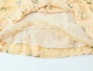 Dettaglio dell'abito floreale a quadri gialli con bordo in pizzo e trama in chiffon