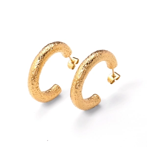 Detail view of gold C-shape earrings with unique hammered lava texture and glossy finish